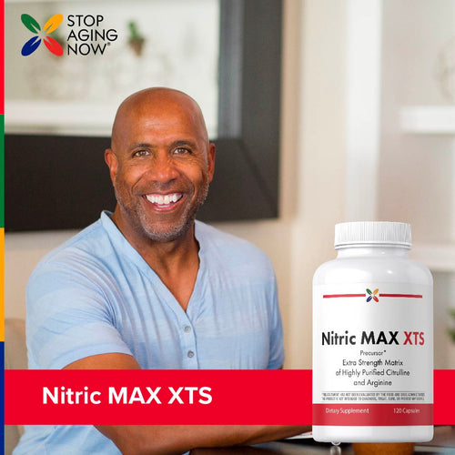 View 8 Man smiling with a supplement bottle labeled 'Nitric MAX XTS' in a home setting.